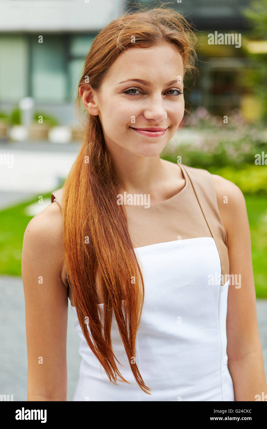 Sorridente giovane donna con lunghi capelli bruna all'aperto Foto Stock
