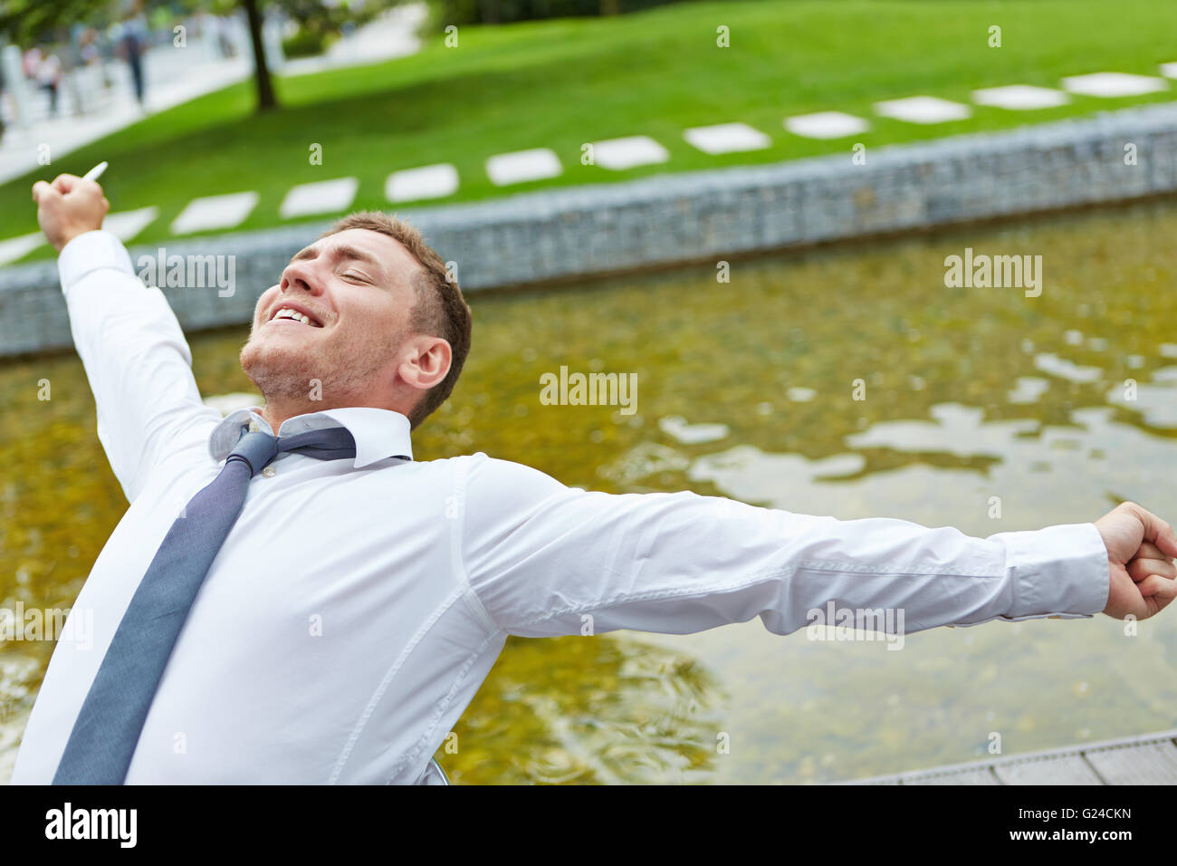 Rilassata business man stretching braccia all'aperto su una sedia Foto Stock