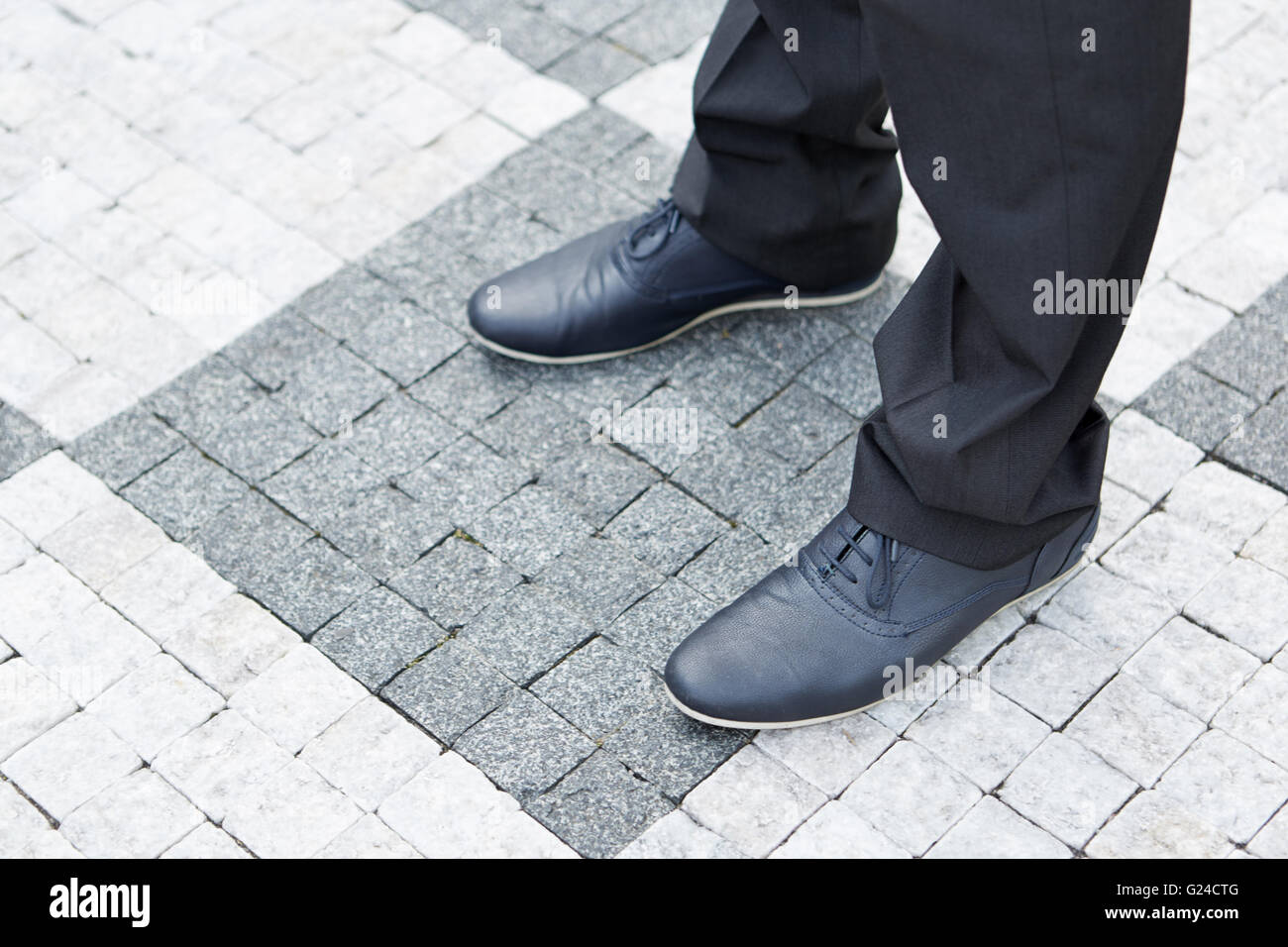 Scarpe di un business man standing sulla pavimentazione stradale Pietre Foto Stock