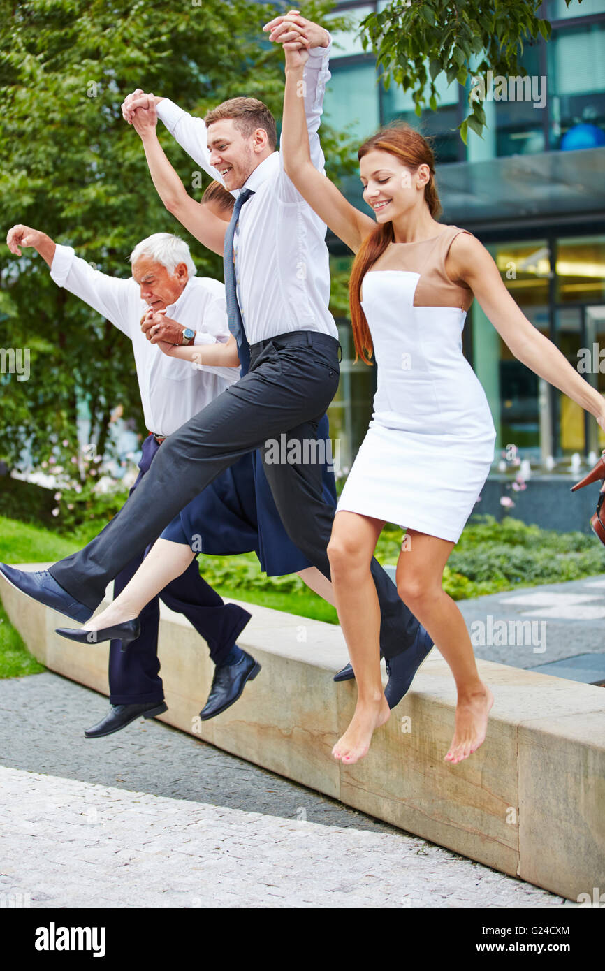 Happy business team jumping insieme su un ostacolo all'aperto Foto Stock