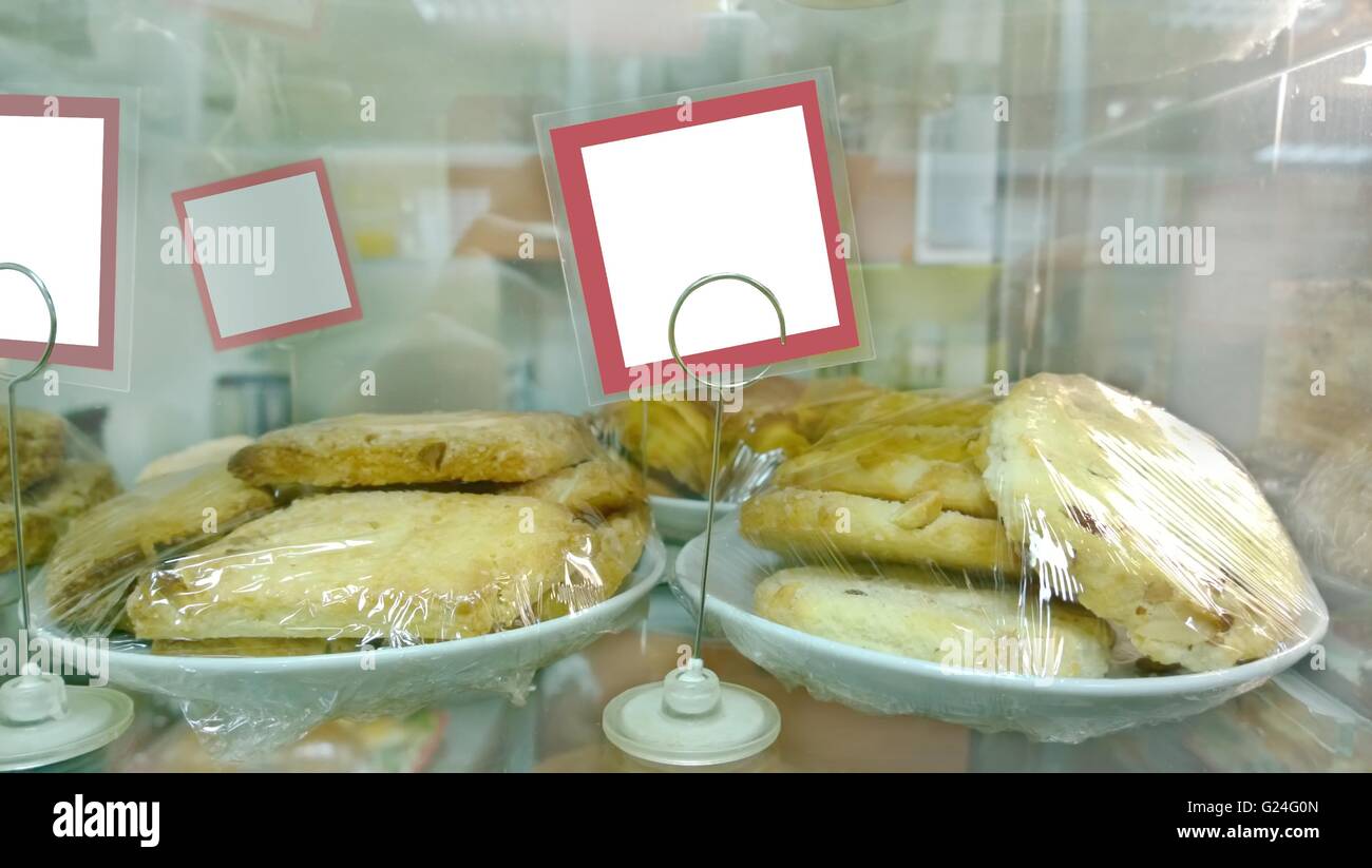 I cookie in pellicola alimentare alla finestra di visualizzazione nel panificio con vuoto prezzo di etichetta Foto Stock