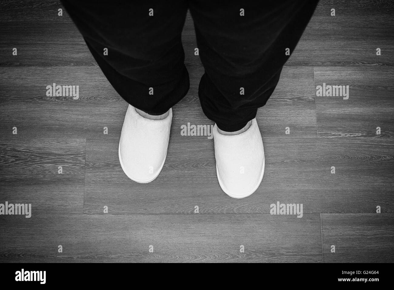 Gambe maschio in bianco pantofole stand sul parquet, immagine monocromatica Foto Stock