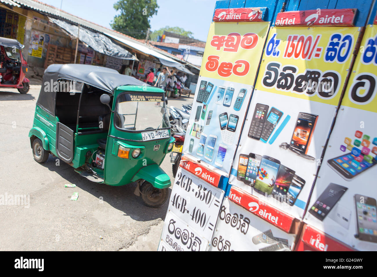 Tangalle , città nel distretto di Hambantota, sud della provincia, Sri Lanka, un tuk tuk rickshaw parcheggiato di fianco a un negozio di telefono Foto Stock