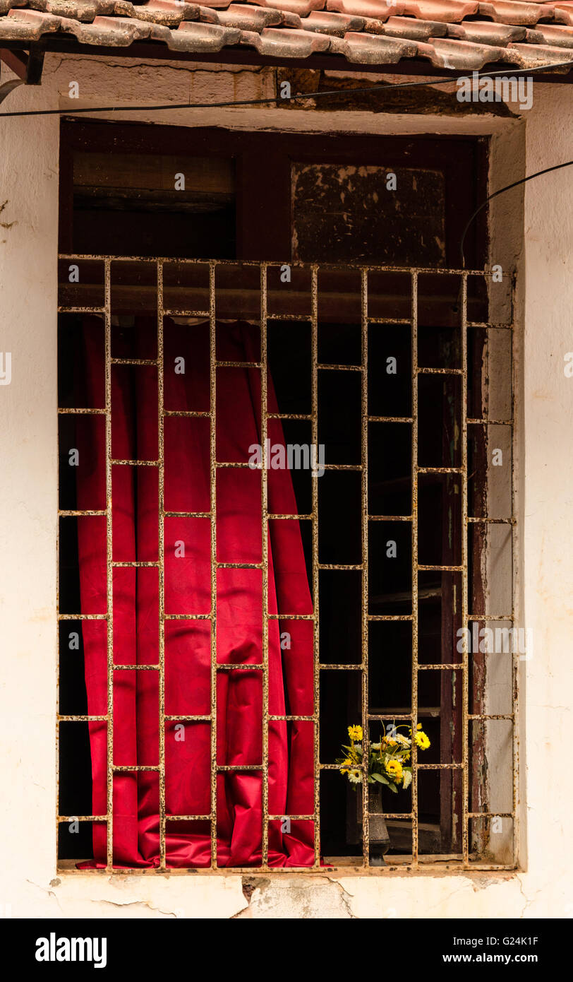 In prossimità di una finestra con griglia di ferro e tende rosse di una vecchia casa portoghese in Fontainhas, Panaji (Panjim), Goa, India Foto Stock