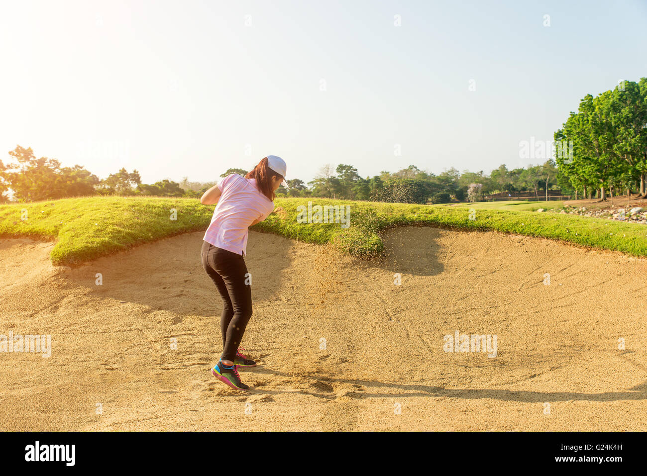 Donna asiatica golfista colpire la pallina da golf fuori da una trappola di sabbia Foto Stock