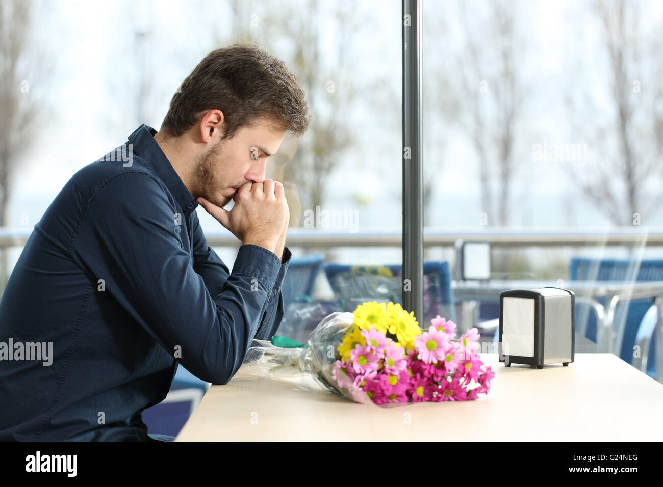 Triste uomo Con mazzo di fiori si alzò in una data con la sua fidanzata in un coffee shop Foto Stock