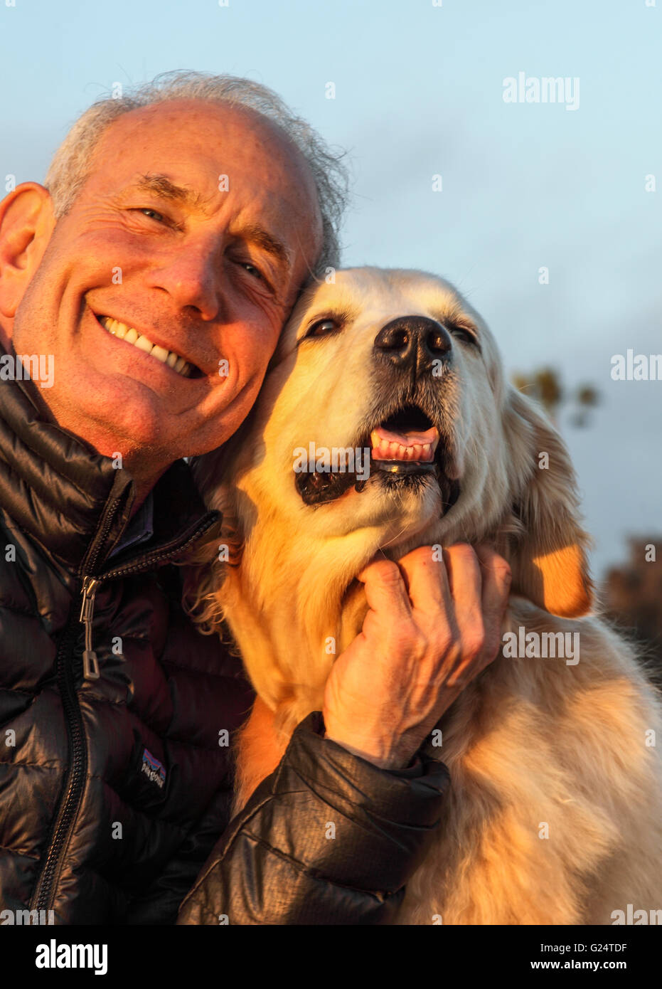 L'uomo abbraccia il suo cane al tramonto Foto Stock