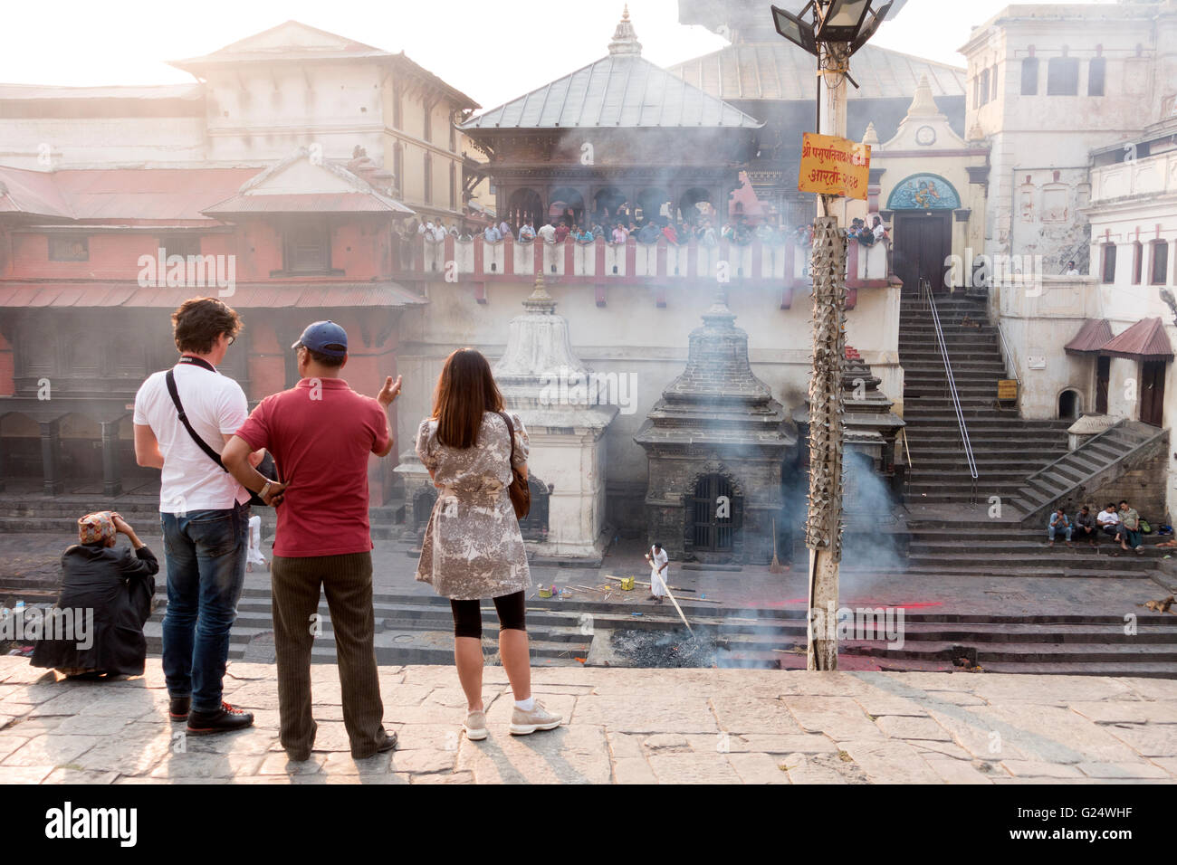 I turisti presso il Tempio di Pashupatinath guardando cremazioni, Kathmandu, Nepal Foto Stock