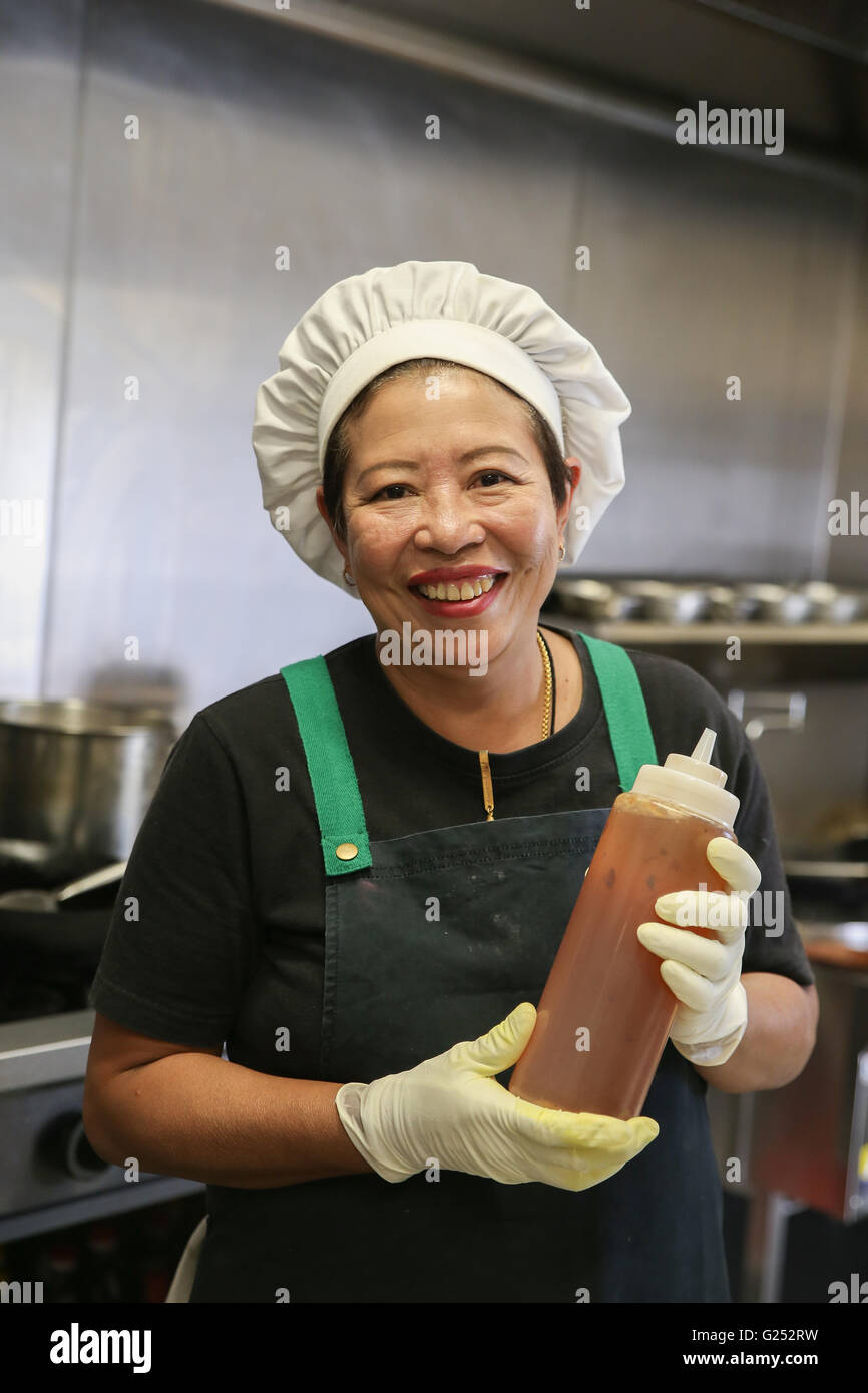 Donna asiatica chef tenendo la bottiglia di salsa Foto Stock