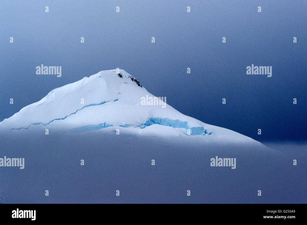 Montagne incappucciate di neve nelle nuvole Paradise Bay, Antartide Foto Stock