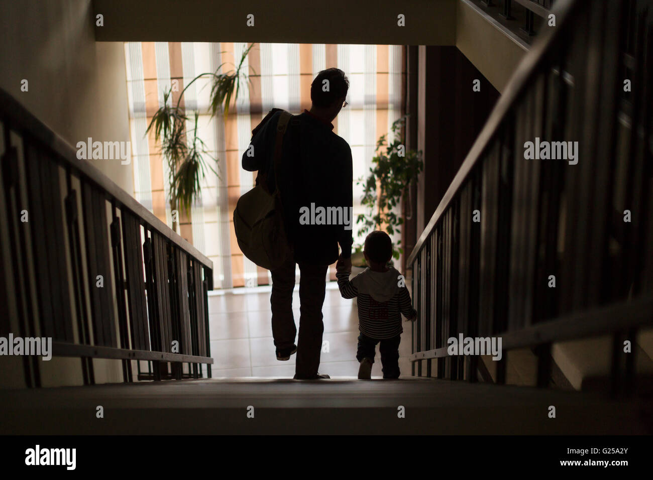 Padre e figlio a piedi giù per le scale tenendo le mani Foto Stock