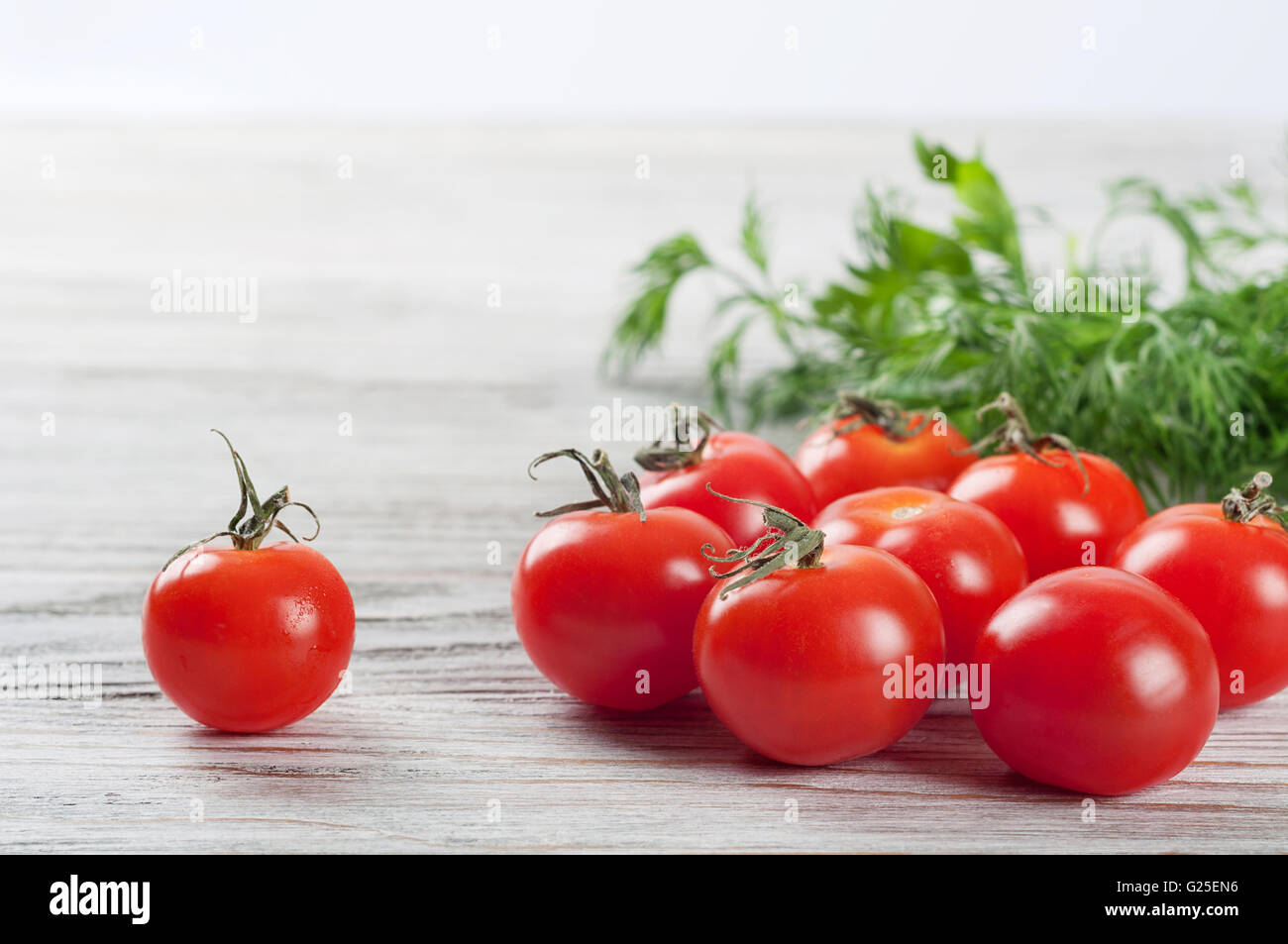 Pomodori ciliegia e aneto verde su un tavolo di legno Foto Stock