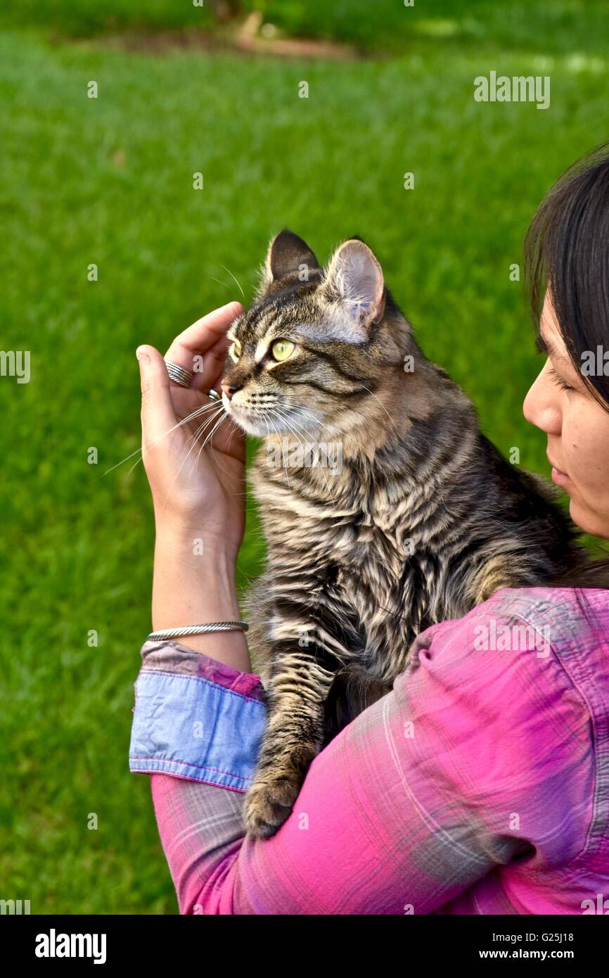 Donna che mantiene un cute cat nelle sue braccia mentre fuori nel cortile Foto Stock