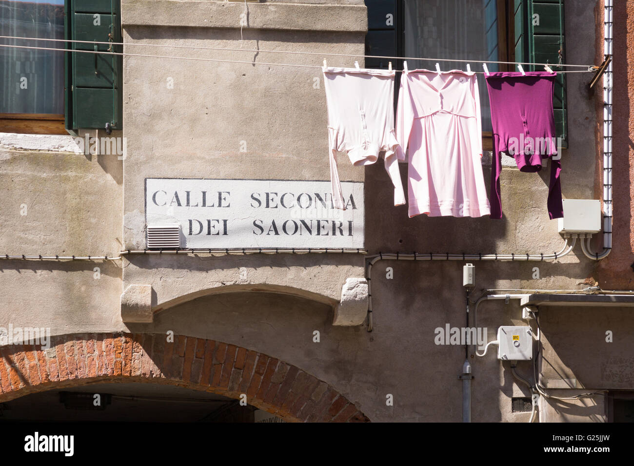 Non è solo un turista a Venezia; il lavaggio dei residenti appesi a una linea di vestiti accanto a un cartello in italiano su una strada secondaria a Venezia, Italia Foto Stock