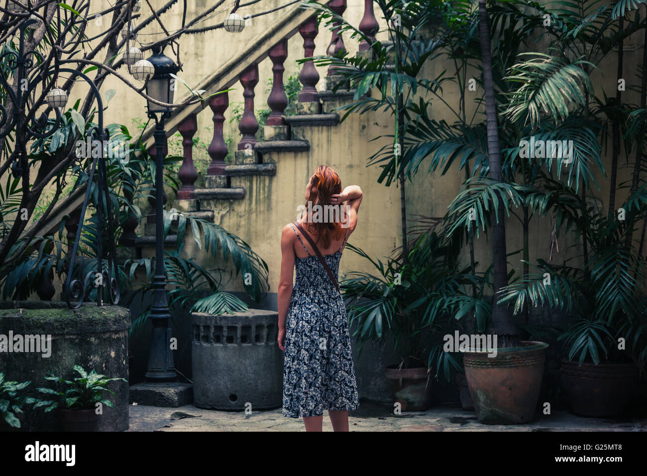 Una giovane donna è ammirando una vecchia scala coloniale in un cortile Foto Stock