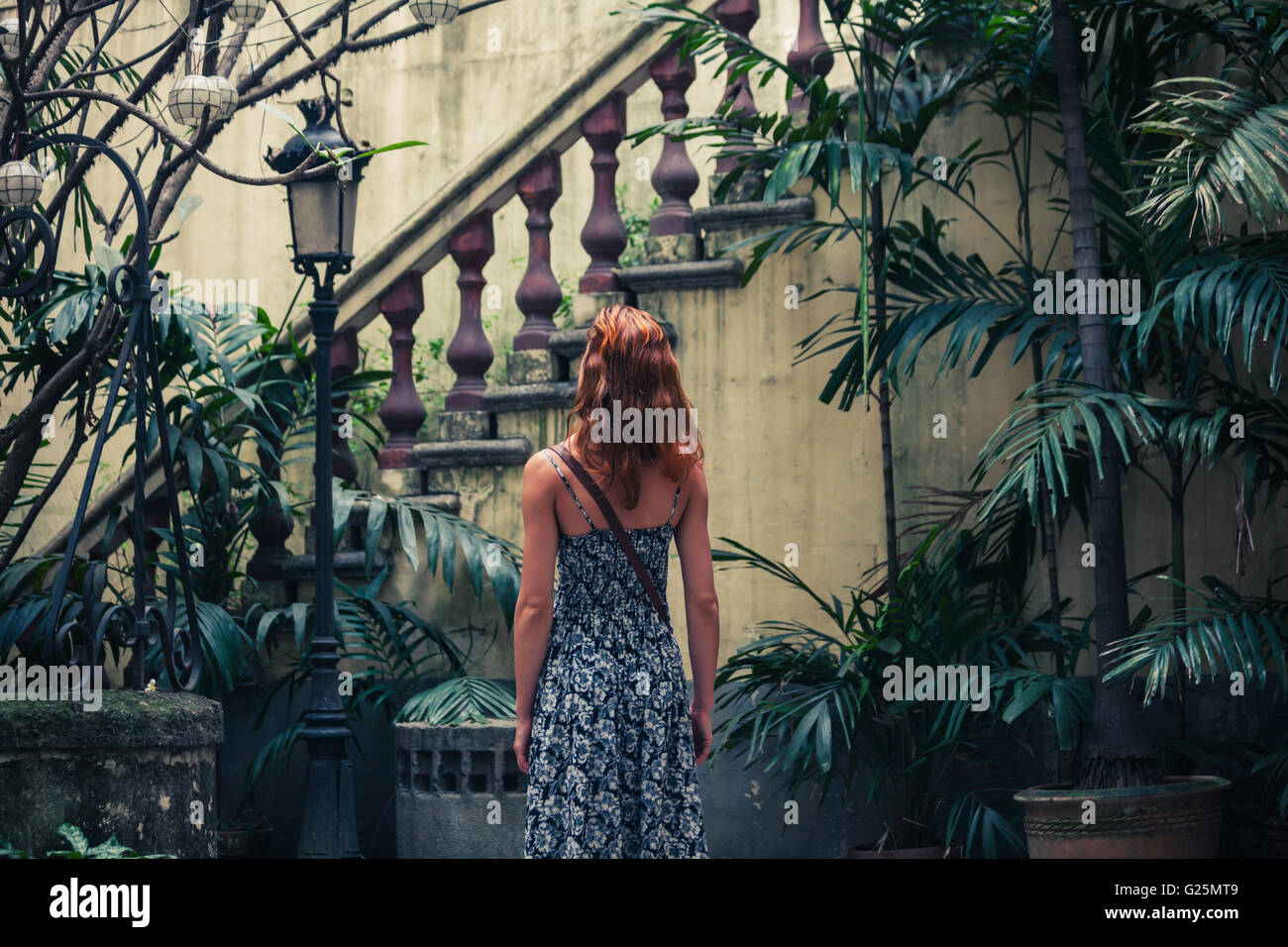 Una giovane donna è ammirando una vecchia scala coloniale in un cortile Foto Stock
