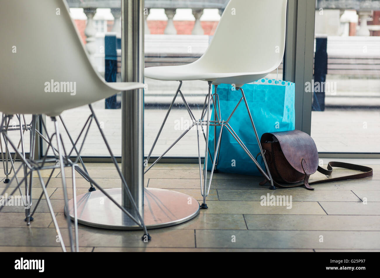 Un shoulderbag abbandonati e sacchetto di shopping per la finestra in un cafe Foto Stock