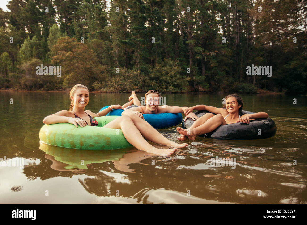 Ritratto di felice giovani adulti sui tubi interni nel lago. Amici godendo una giornata al lago. Foto Stock