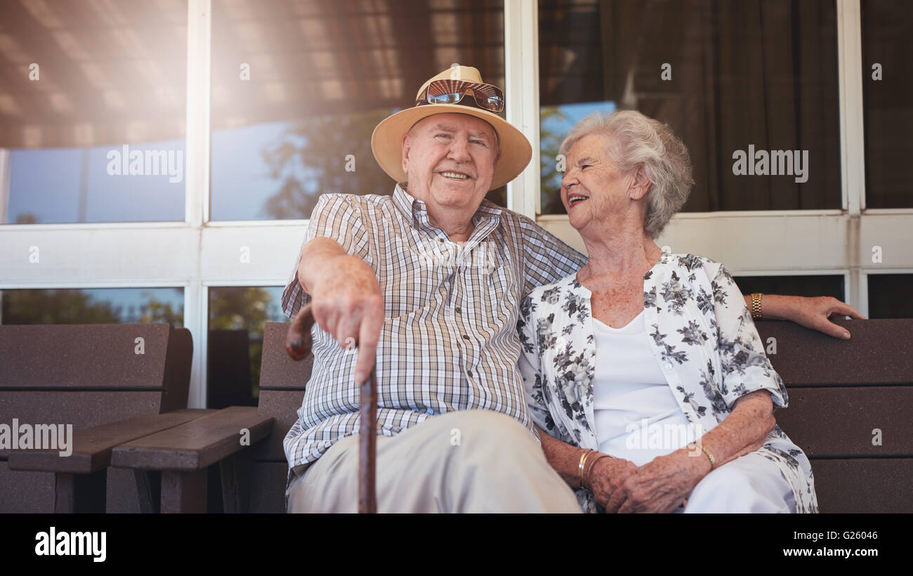 Ritratto di bello senior uomo seduto con la moglie su un banco di lavoro al di fuori della loro casa. Coppia in pensione prendendo una pausa e rilassarsi Foto Stock