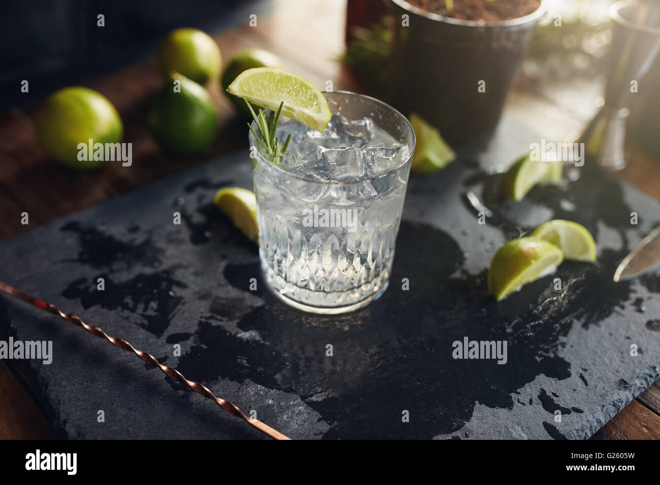 Close up appena fatti e gin tonic bevanda con le fette di limone e il cucchiaio su una scheda di colore nero. Foto Stock