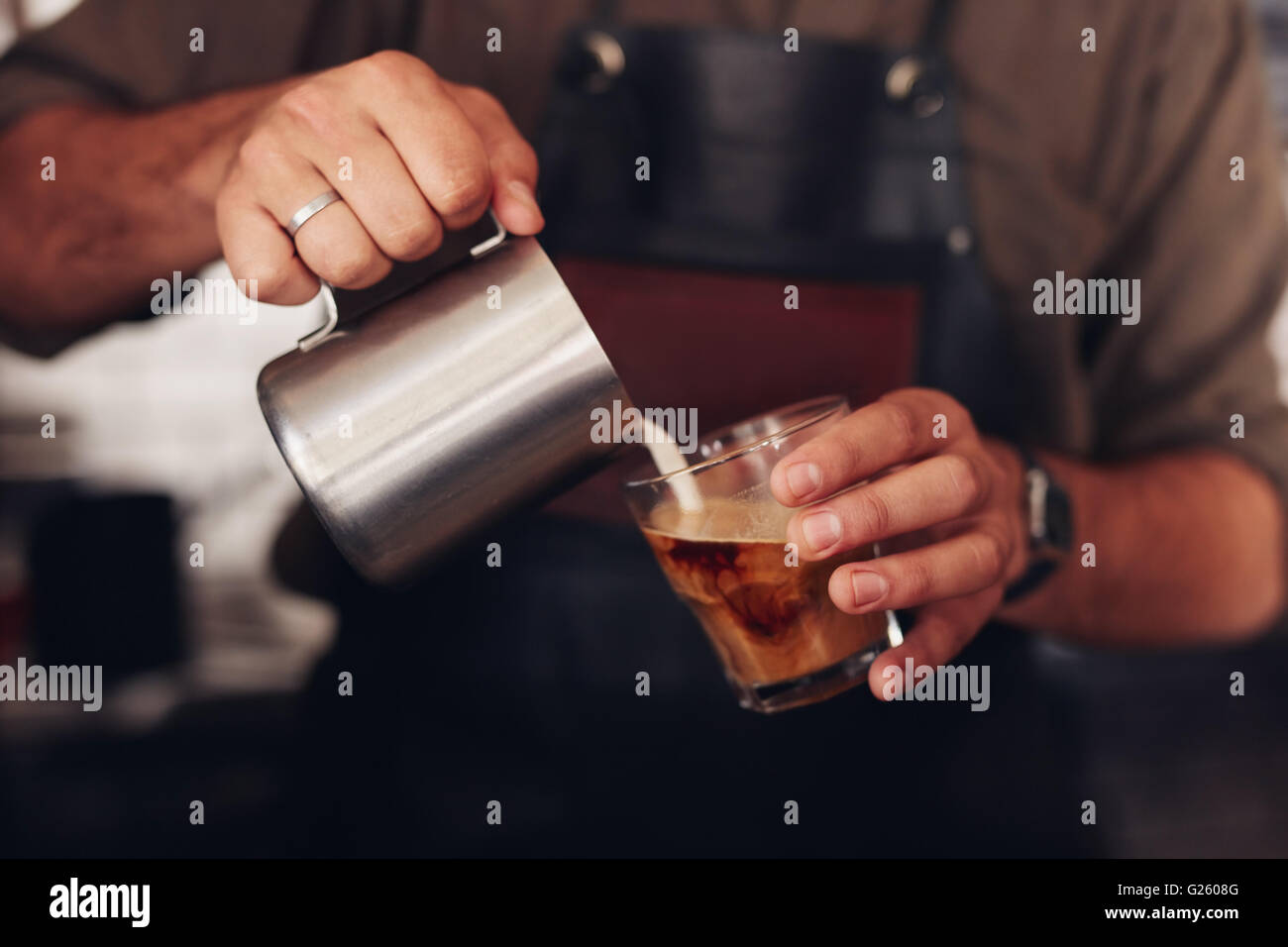 Ritagliato shot di caffè è preparato da un barista. Concentrarsi sulle mani tazza di caffè e latte jar. Foto Stock
