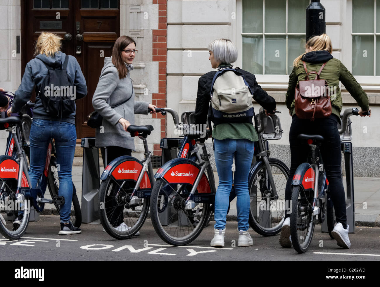 Le giovani ragazze parcheggio biciclette a Santander Noleggio cicli di docking station in Westminster, Londra England Regno Unito Regno Unito Foto Stock