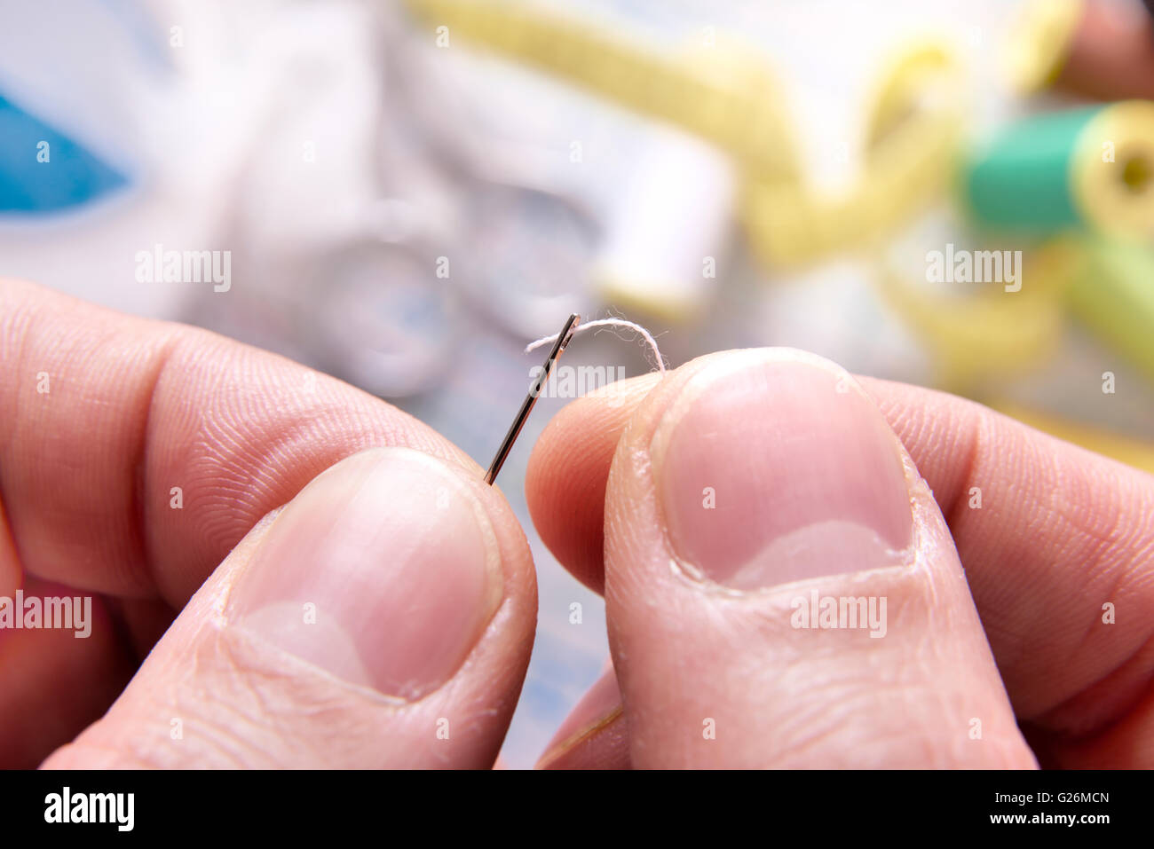 Dita di una filettatura su misura un ago. Composizione orizzontale. Close up Foto Stock