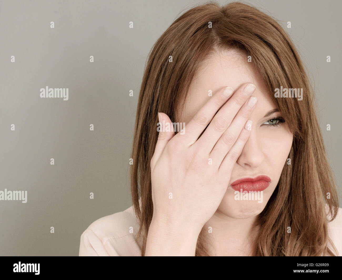 Ritratto di un triste giovane donna che copre un occhio con la sua mano cercando triste e miserabile Foto Stock