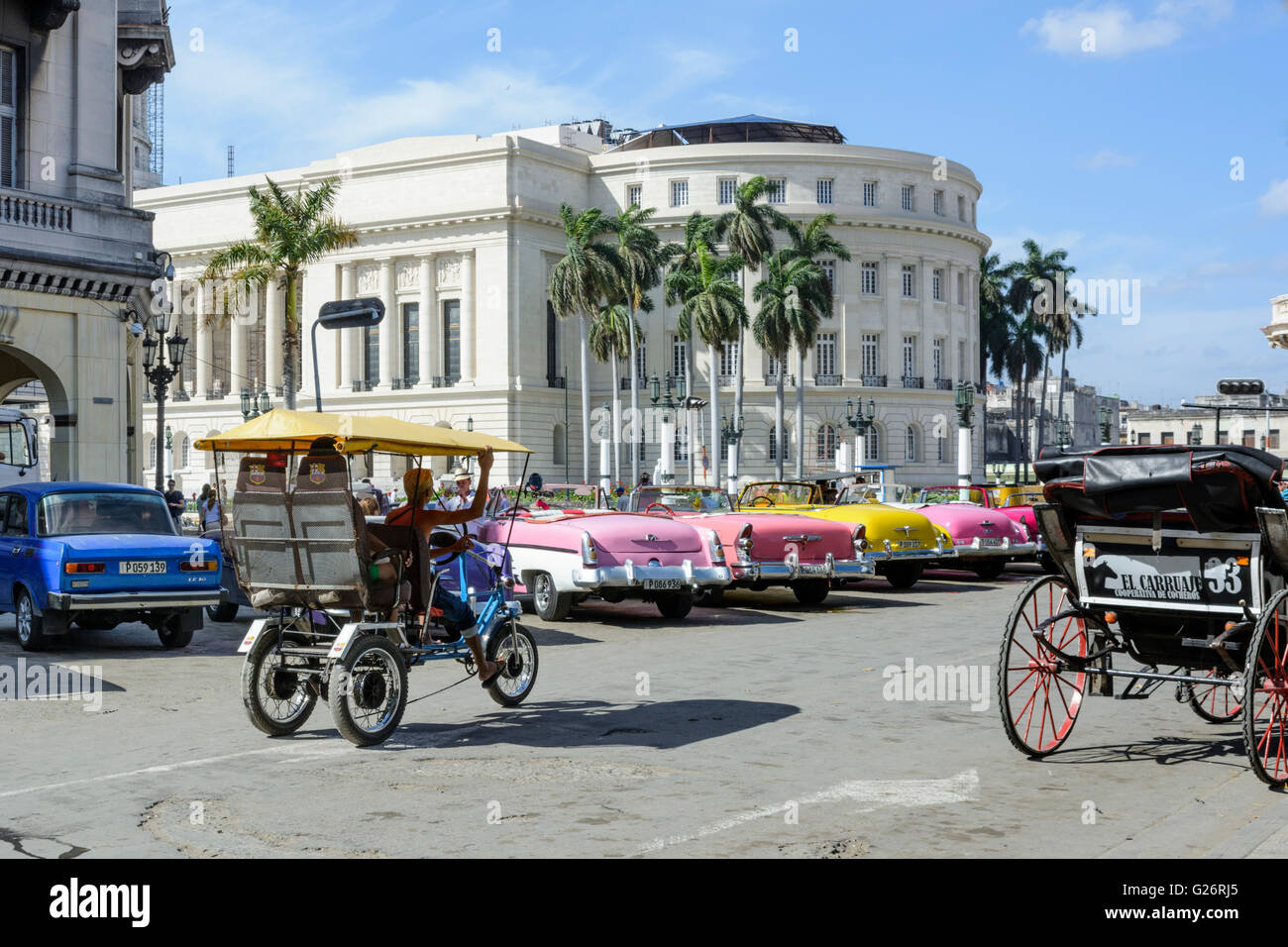 Vintage American cars e una bicicletta taxi fuori la National Capitol Building (Capitolio) nel Parque Central Havana, Cuba Foto Stock