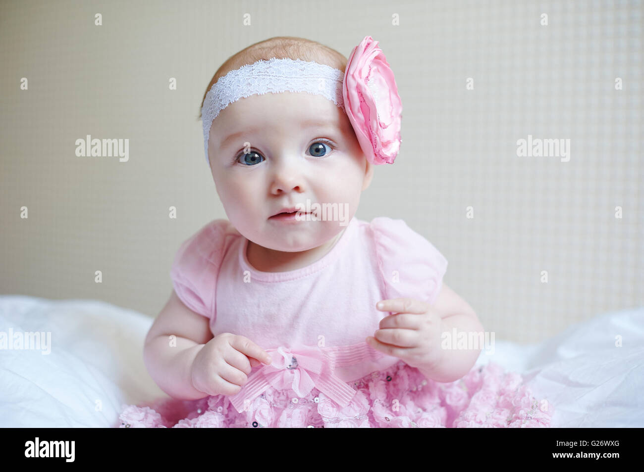 Carino bellissimo bambino ragazza seduta su un letto in abito rosa Foto Stock