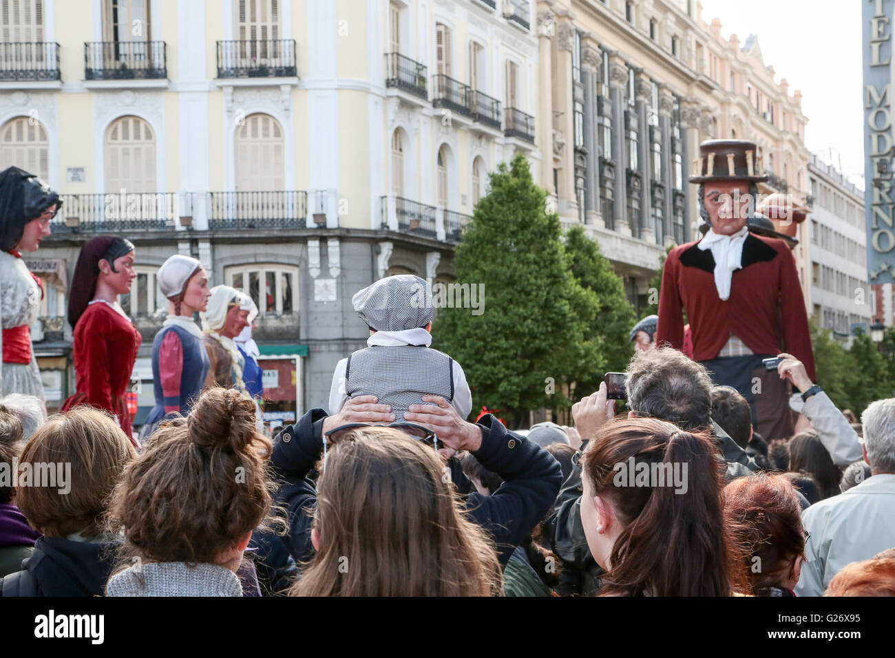 Un bambino vestito in abiti tradizionali su qualcuno alle spalle la visione di San Isidro fiestas a Madrid, Spagna. Viste generali in Foto Stock
