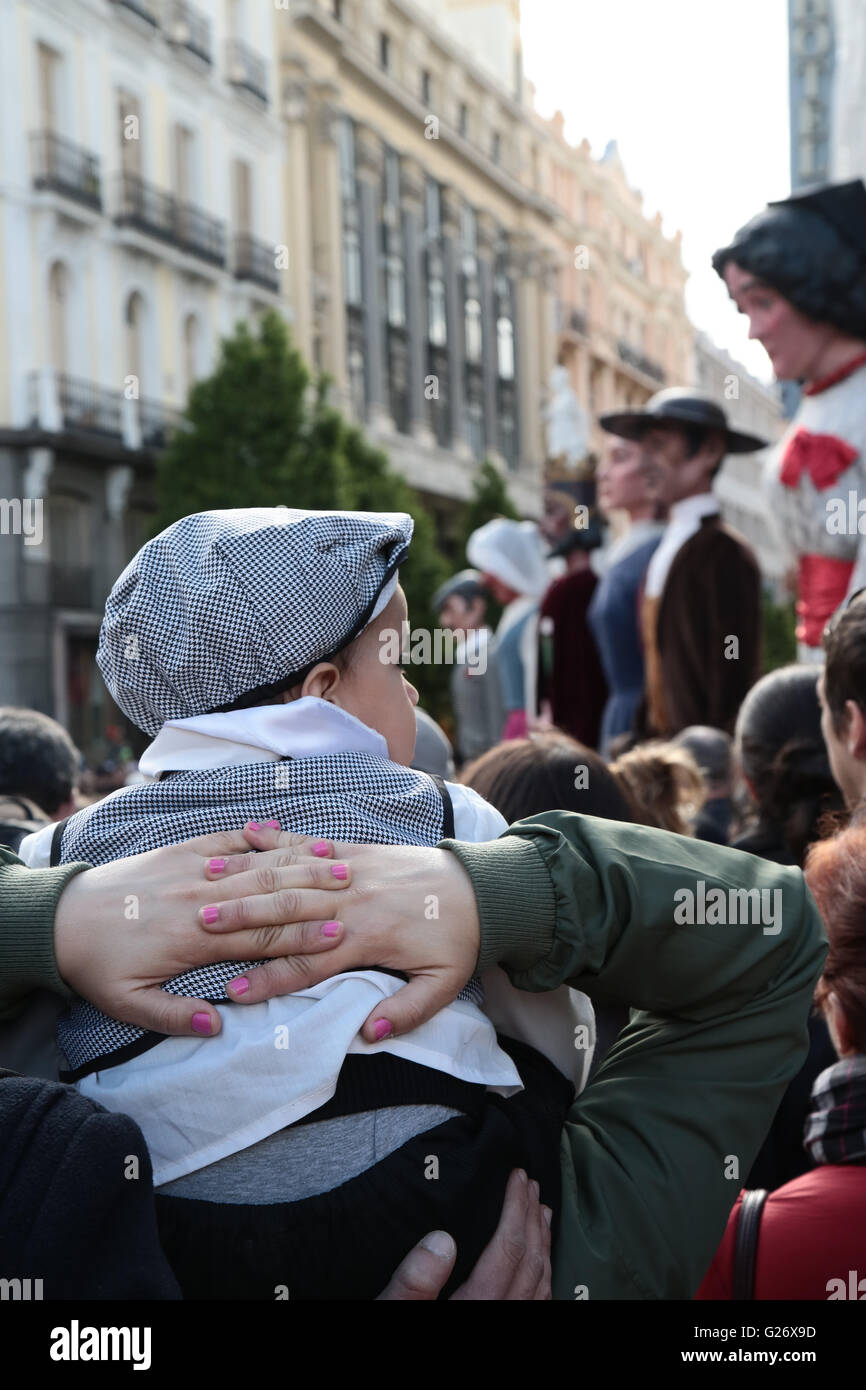 Un bambino vestito in abiti tradizionali su qualcuno alle spalle la visione di San Isidro fiestas a Madrid, Spagna. Viste generali in Foto Stock