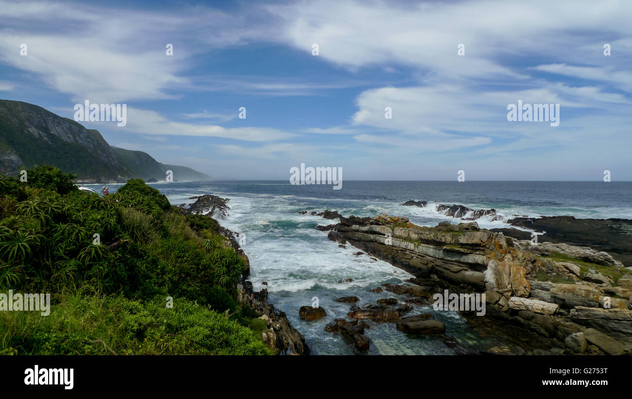 Spiaggia rocciosa tsitsikama oceano onde scenario skyline nuvole in contrasto tra di loro in Sud Africa Foto Stock