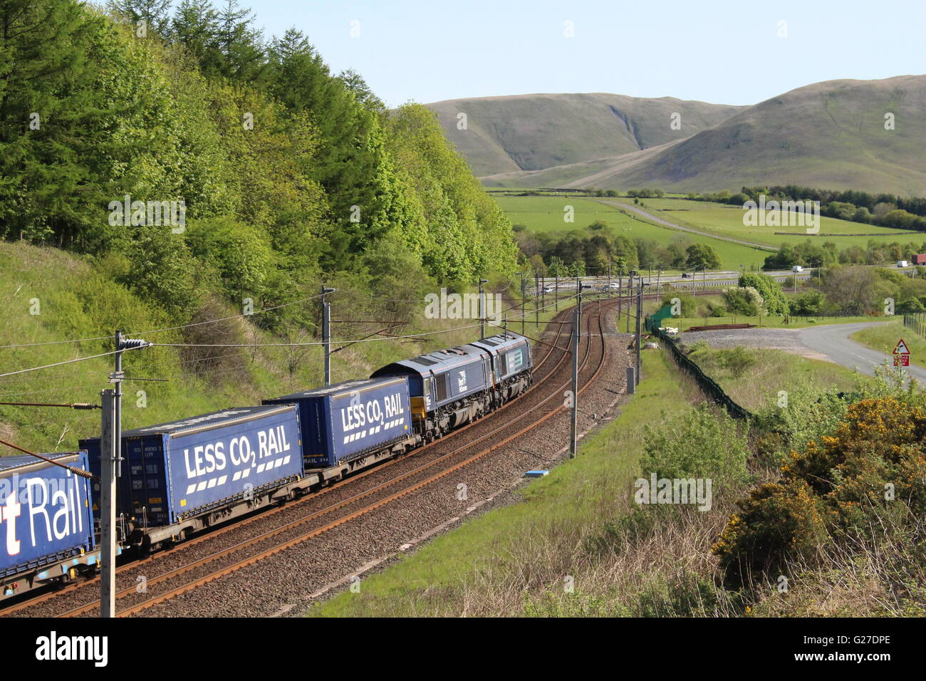 Due della classe 66 locomotive diesel in diretta i servizi ferroviari livrea con il Tesco di treno sulla WCML vicino Beckfoot in Cumbria. Foto Stock