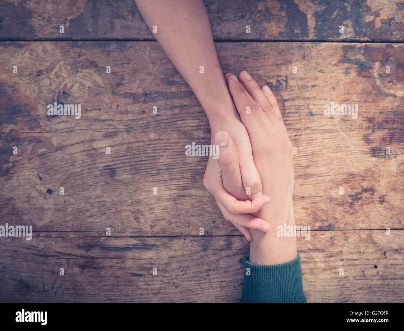 Chiudere fino a un uomo e una donna si tengono per mano a un tavolo di legno Foto Stock