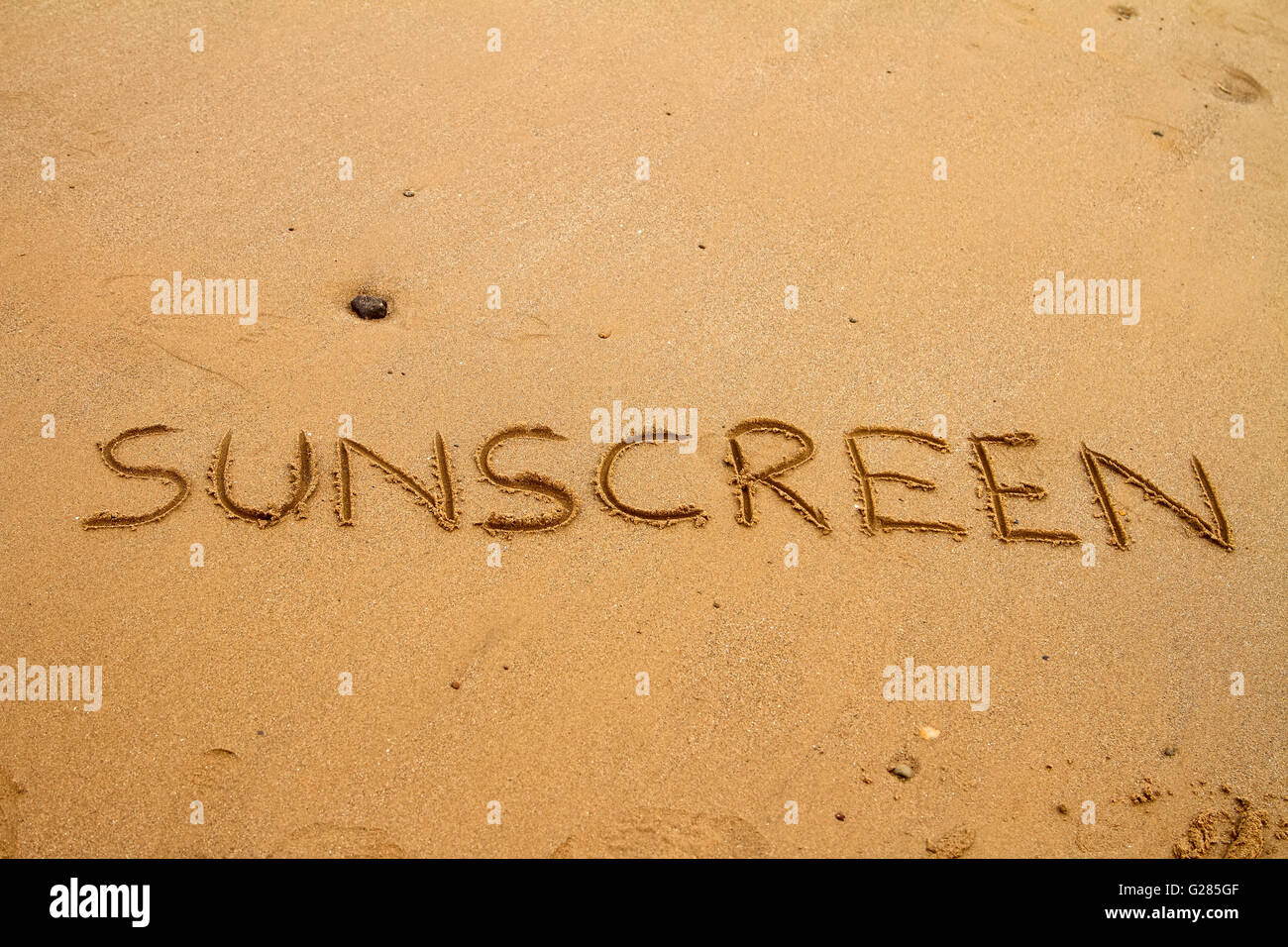 La parola sunscreen scritto nella sabbia su una spiaggia in una giornata di sole presso la costa Foto Stock