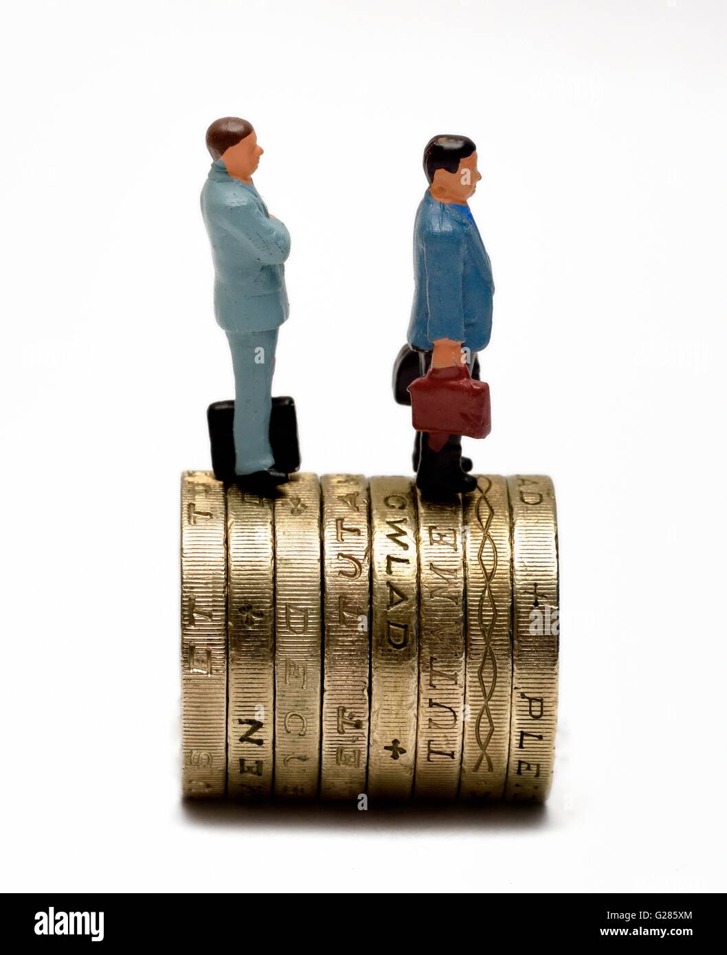Miniatura di figurine di uomini di affari in piedi sulla sommità del british una libbra di monete. Foto Stock
