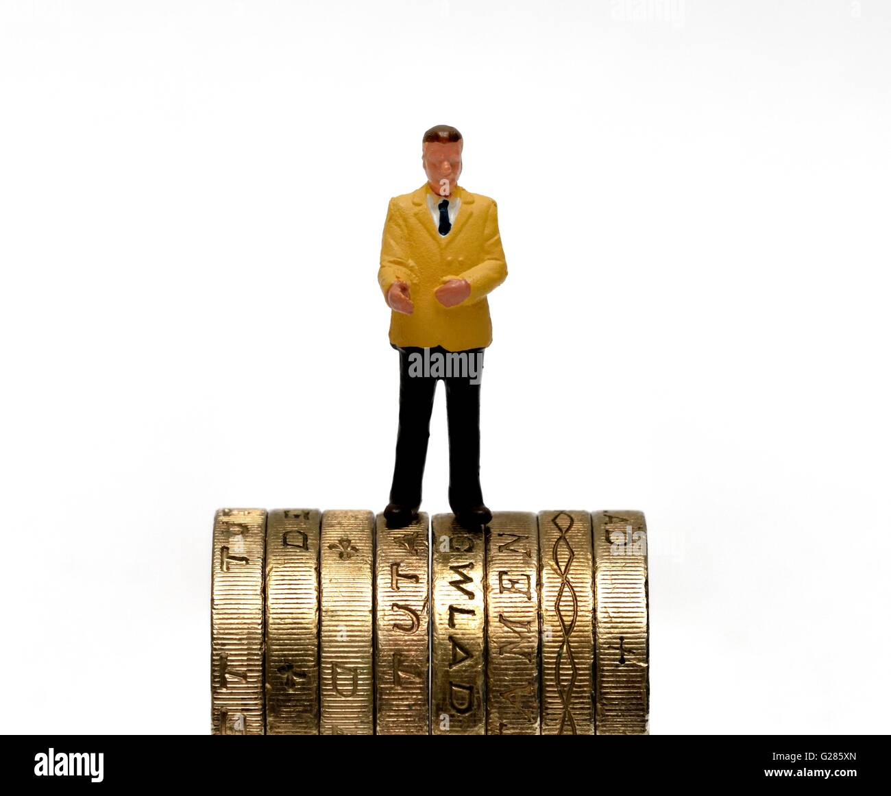 Statuetta in miniatura business man in piedi sulla sommità del british una libbra di monete. Foto Stock