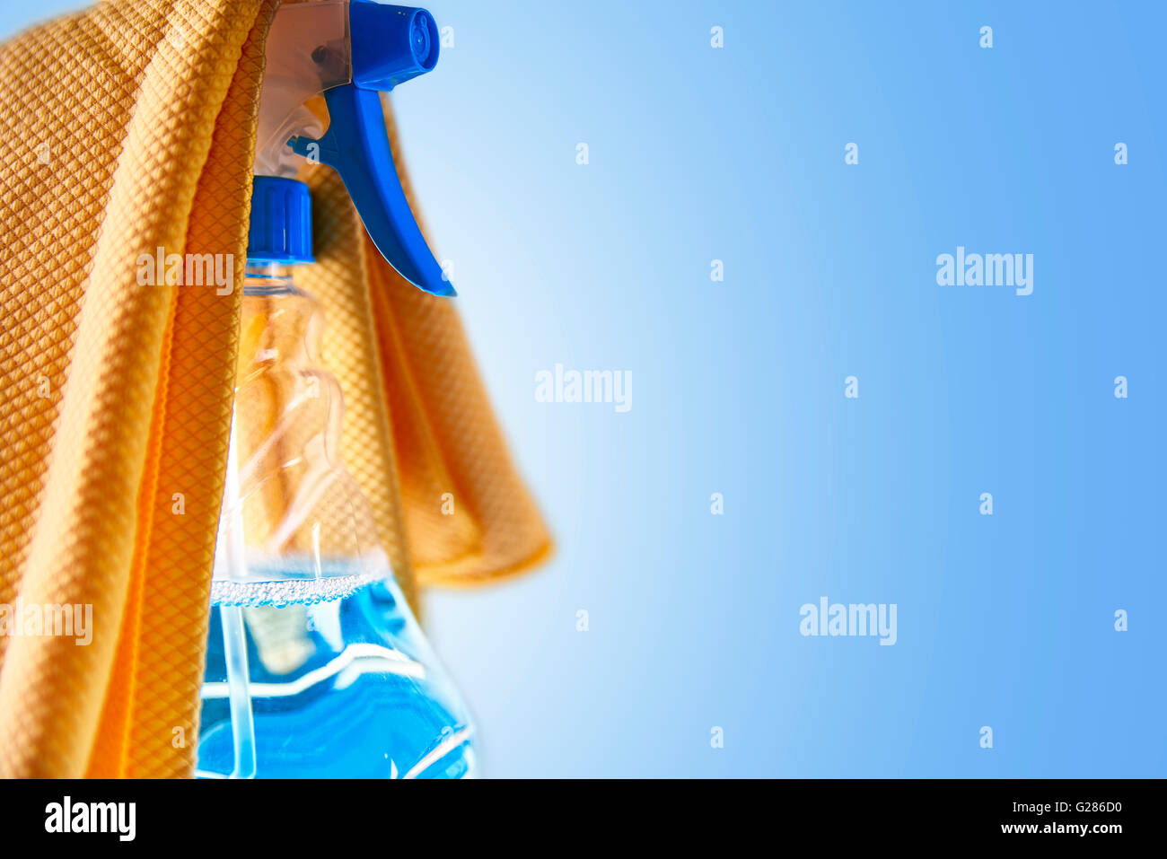 Detergente per vetro flacone spray e panno giallo con sfondo blu. Il concetto di pulizia.composizione orizzontale. Foto Stock