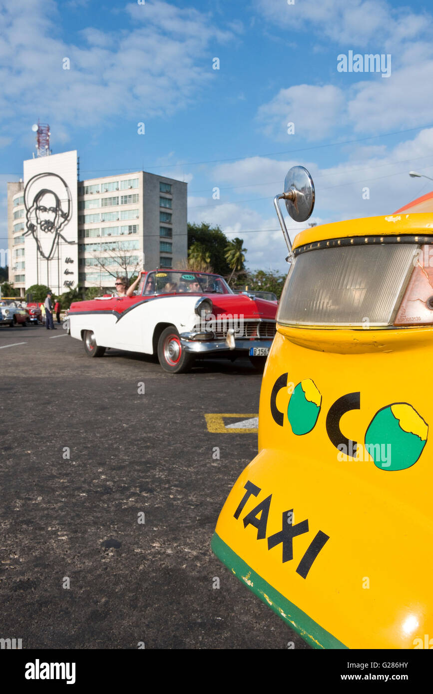 Un taxi coco, americano anni cinquanta taxi auto medio e l'immagine di Camilo Cienfuegos sulla costruzione di sfondo sulla Piazza della Rivoluzione. Foto Stock