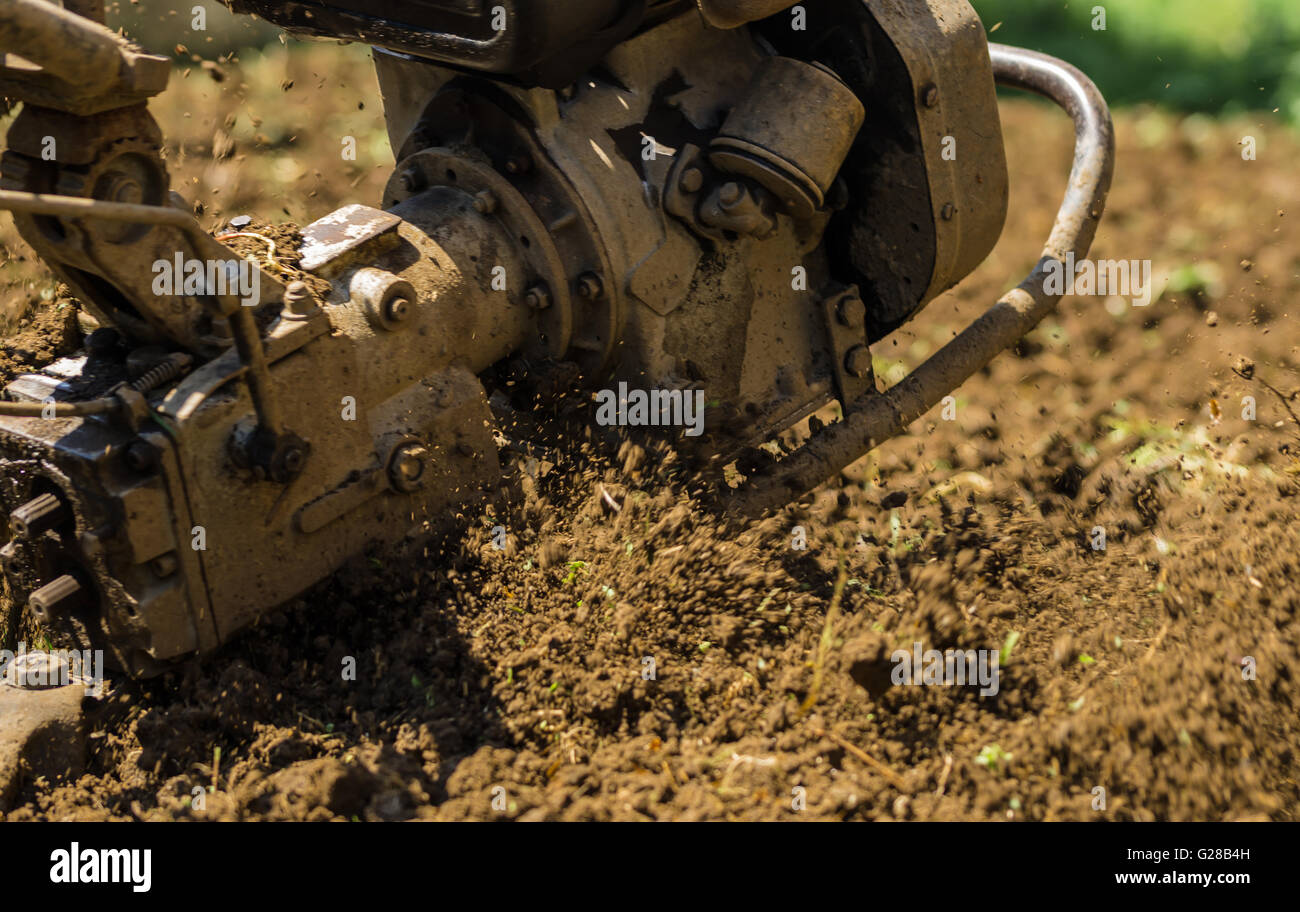 Agricoltore utilizzando la macchina mart coltivatore per arare il terreno Foto Stock