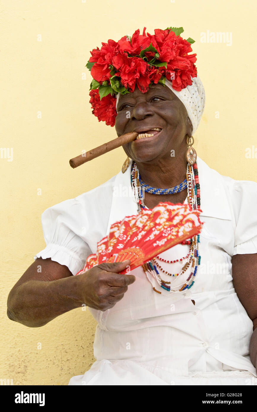 Una visione comune nella vecchia città di Havana a Cuba - normalmente una signora anziana sarà vestito in abiti tradizionali "fumare un sigaro Foto Stock