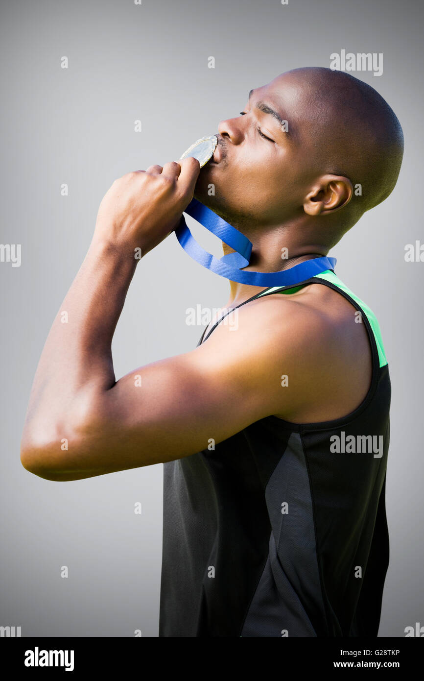 Immagine composita della vista laterale di atletica uomo baciando la sua medaglia d argento Foto Stock