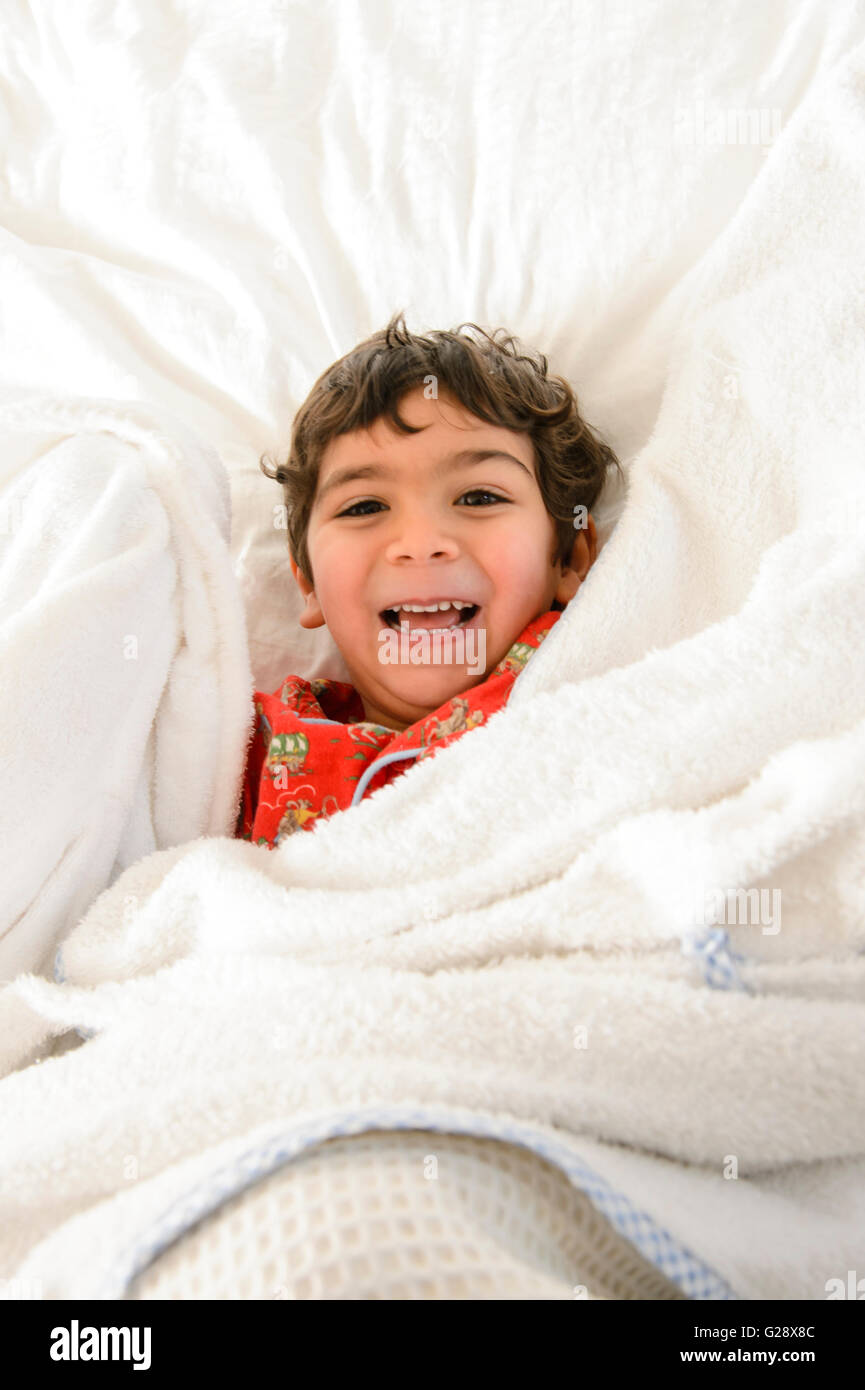 Kid giocando sul letto in un pijama Foto Stock