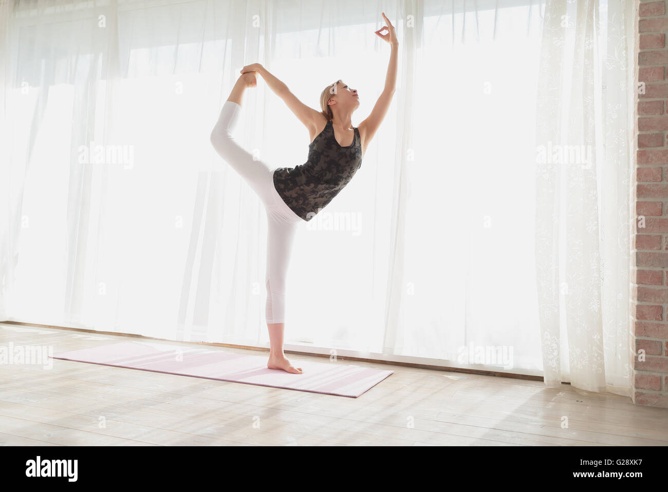 Attraente giovane giapponese la pratica dello yoga in una stanza ariosa Foto Stock