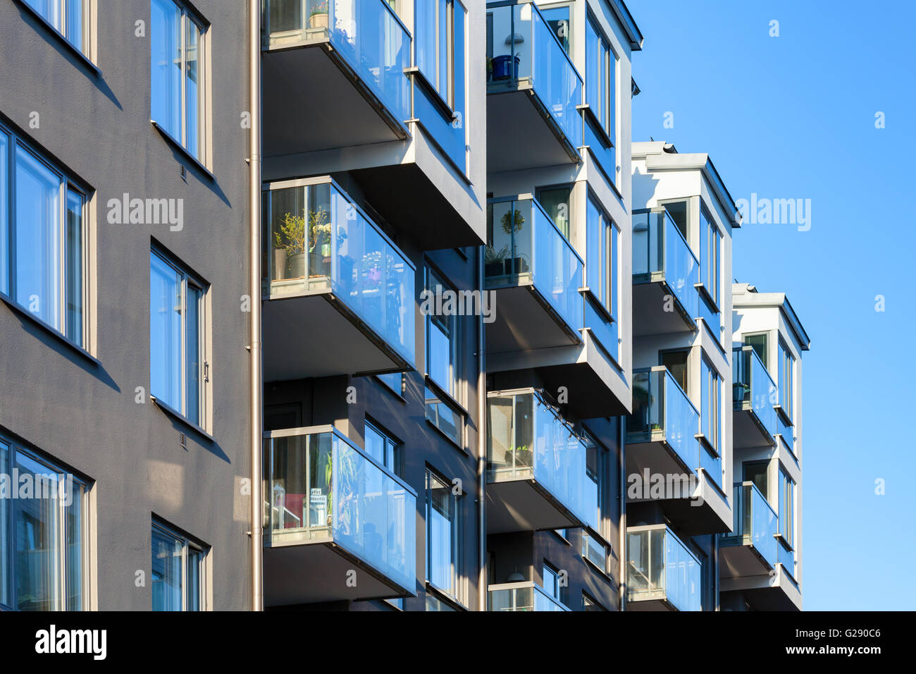 Frammento astratto di architettura contemporanea, balconi con ringhiere in vetro e splendente di windows Foto Stock