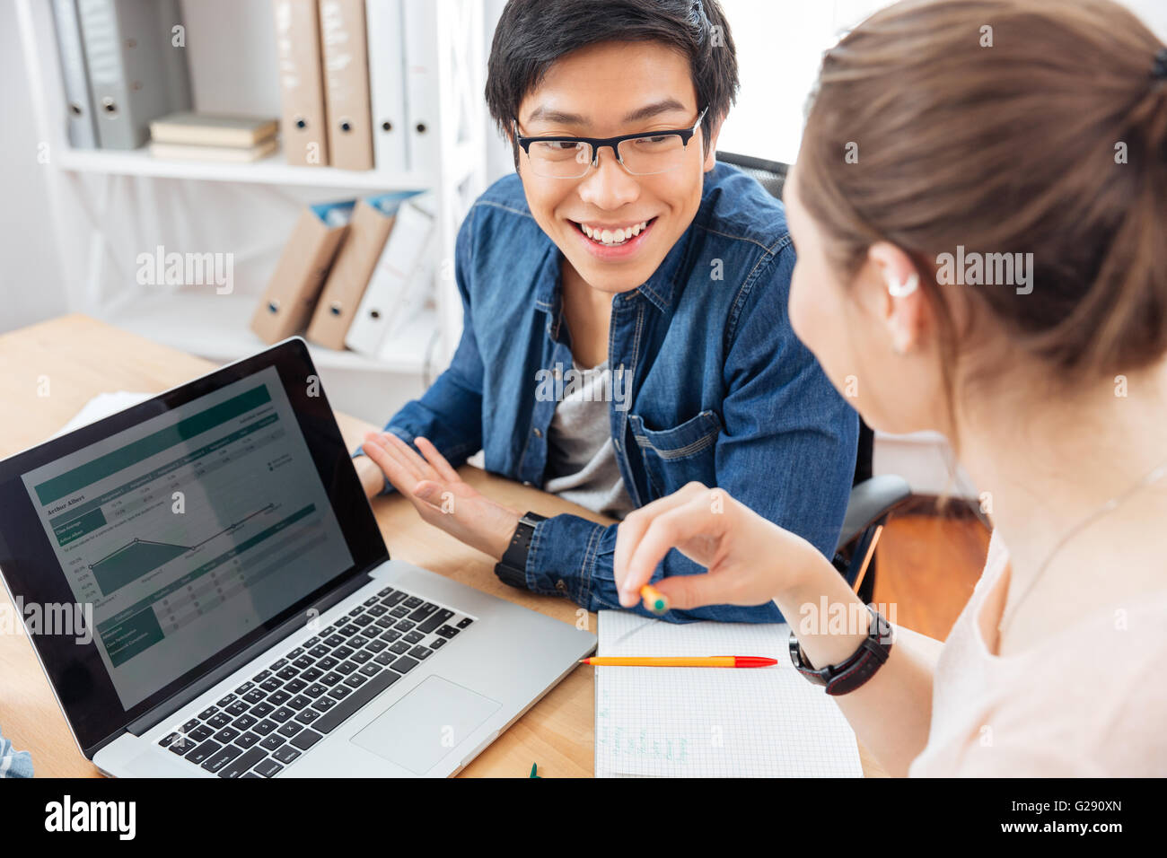 Felice di due giovani imprenditori utilizzando laptop e lavorare insieme Foto Stock