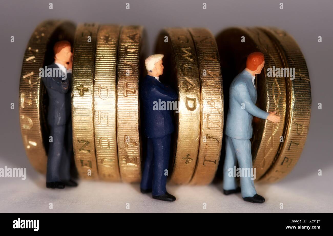 Miniatura di figurine di uomini di affari in piedi fra british una libbra di monete. Foto Stock
