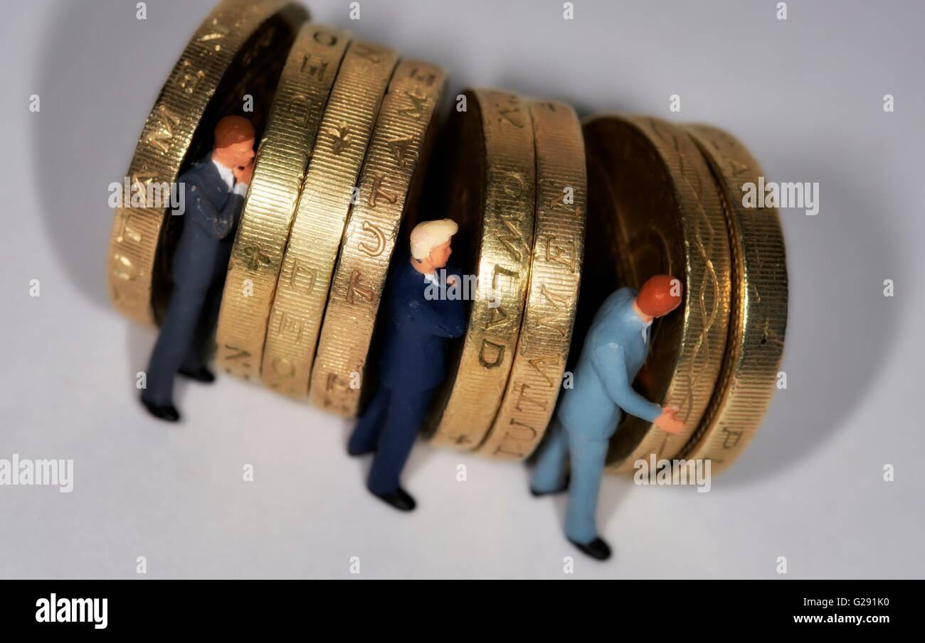 Miniatura di figurine di uomini di affari in piedi fra british una libbra di monete. Foto Stock