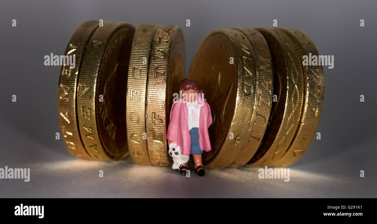 Statuetta in miniatura ragazza in piedi fra british una libbra di monete. Foto Stock